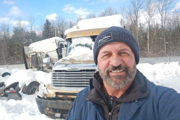 Luc Tourangeau in front of trucks covered by snow