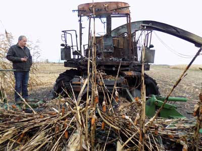 Luc Tourangeau standing beside a burnt harvester machine